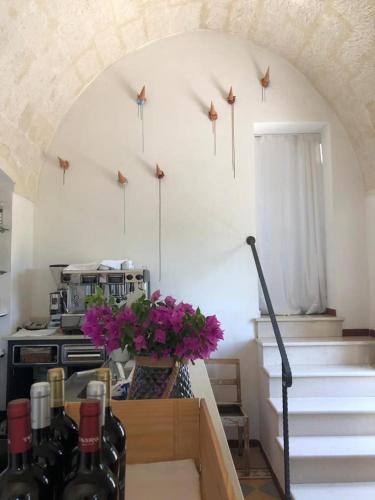 a kitchen with a staircase with flowers and wine bottles at Borgo Valle Rita in Ginosa Marina