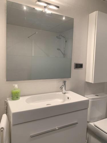 a white bathroom with a sink and a mirror at Apartamento Somos Ainsa in Aínsa