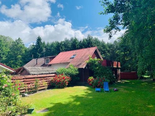 a house with a red roof and a yard with chairs at Adeles sodyba in Sturmai