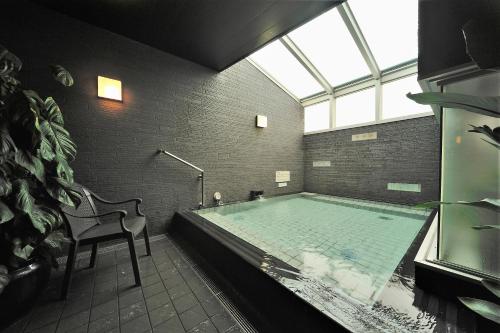 
a bath room with a tub and a bench at Dormy Inn Premium Shibuya-jingumae in Tokyo
