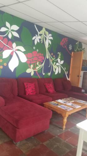 a living room with a red couch and flowers painted on the wall at Luna International Hostel in Estelí