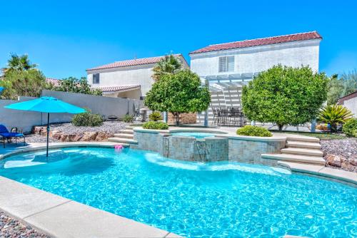 a swimming pool in front of a house with an umbrella at Vegas Vacation in Las Vegas