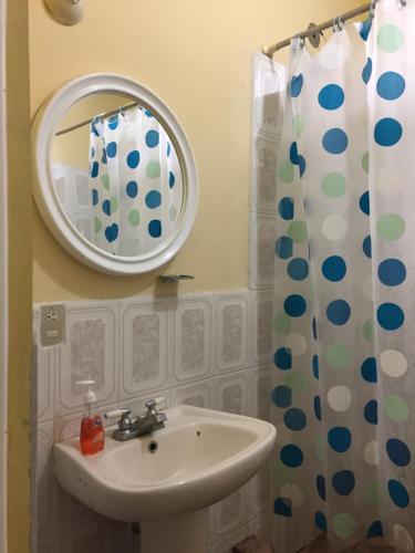 y baño con lavabo, espejo y cortina de ducha. en Casa Verónica a 2 kilometros del IRTRA en Retalhuleu