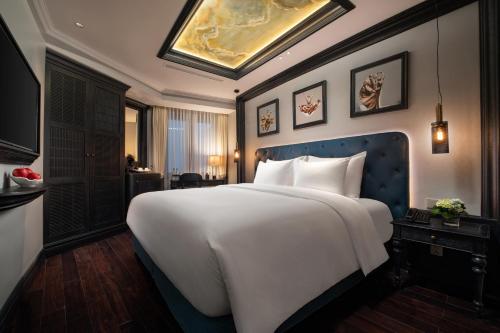 a bedroom with a large white bed with a blue headboard at La Sinfonía del Rey Hotel & Spa in Hanoi