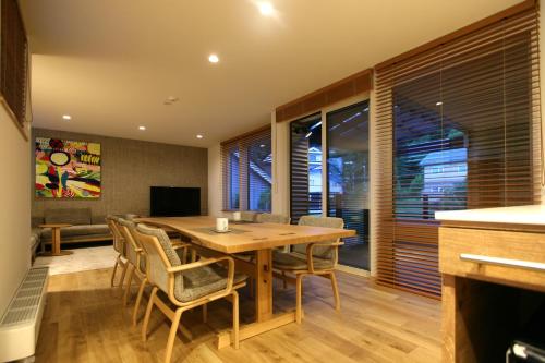 een eetkamer met een houten tafel en stoelen bij Shimogoryo House in Furano