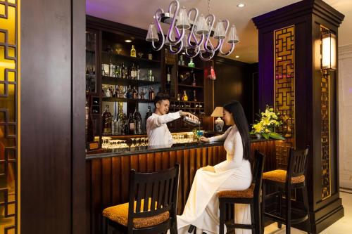 una mujer sentada en un bar con un camarero en Thanh Lich Royal Boutique, en Hue