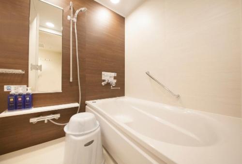a bathroom with a tub and a sink and a mirror at Richmond Hotel Tenjin Nishi-Dori in Fukuoka