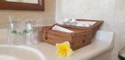 uma cesta de produtos de higiene pessoal e uma flor num lavatório em Melasti Beach Resort & Spa Legian em Legian