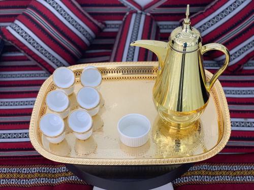a gold tea kettle on a tray with four cups at City Avenue Hotel in Dubai