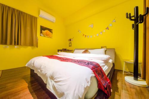 a bedroom with yellow walls and a bed with white sheets at 梅花湖-陽光屋民宿 in Dongshan