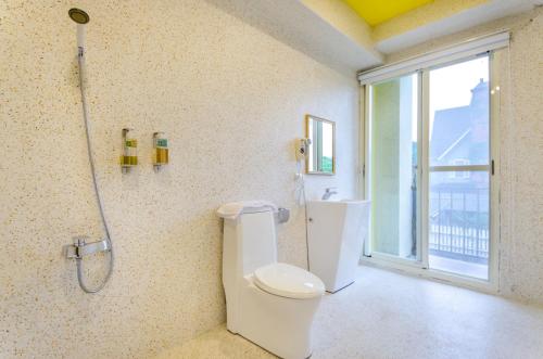 baño con aseo y ducha y ventana en 梅花湖-陽光屋民宿 en Dongshan