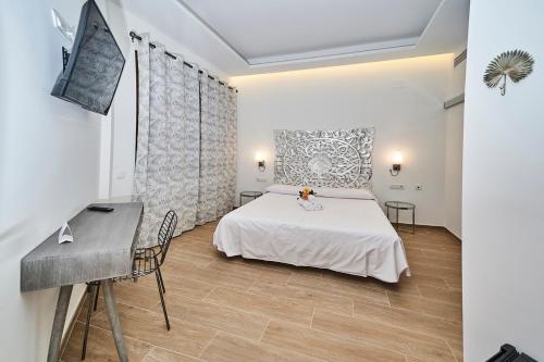 a bedroom with a white bed and a desk at Hotel Bajamar Ancladero Playa in Nerja