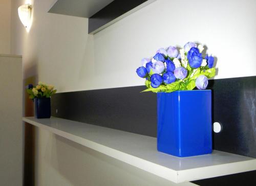 a blue vase filled with purple flowers on top of a white counter at Modern Central-Near Unirii Square in Cluj-Napoca