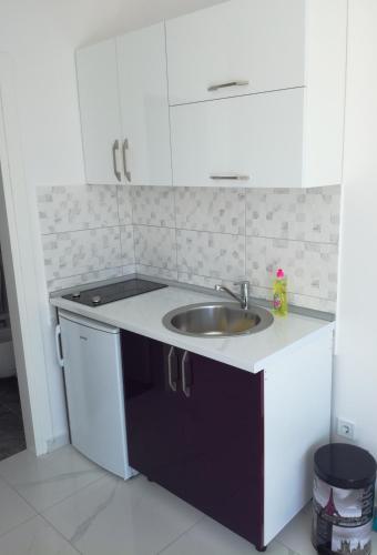 a kitchen with a sink and white cabinets at Olea in Tivat