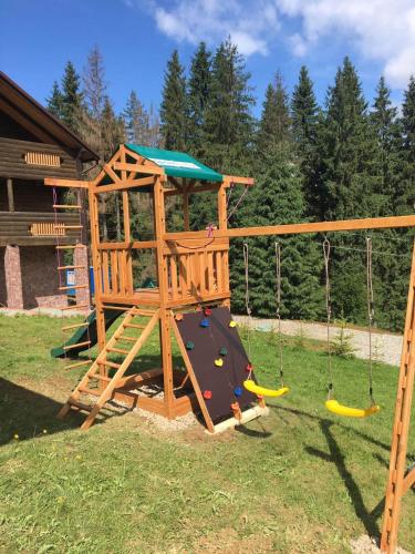a wooden playground with a slide and swings at GUTSULWOOD in Yablunytsya