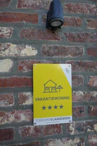un signal d'avertissement jaune sur un mur de briques dans l'établissement Bed & Bets!, à Geetbets
