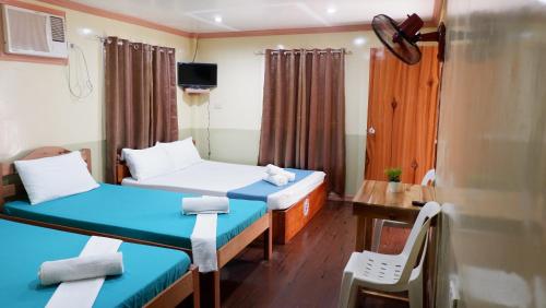 a room with two beds and a table and a desk at Mountain Side Inn in El Nido