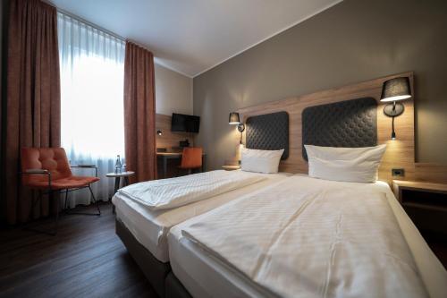 a hotel room with a large bed and a chair at Hotel Hirsch in Kehl am Rhein