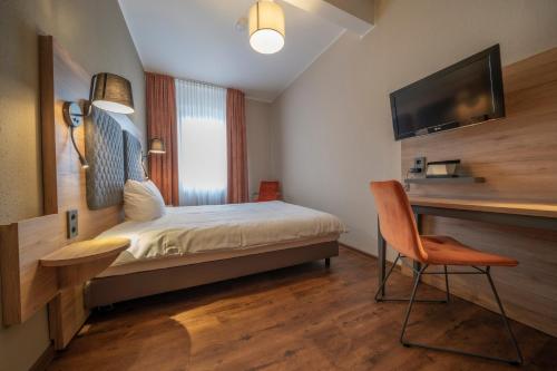 a bedroom with a bed and a desk and a television at Hotel Hirsch in Kehl am Rhein