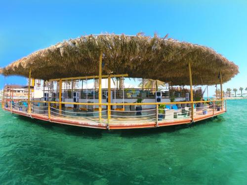 a boat with a straw roof on the water at Lagoona Beach Luxury Resort and Spa in Manama