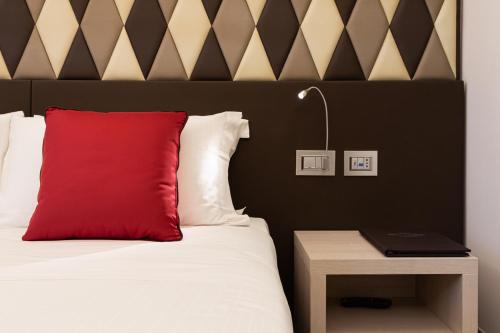 a bed with a red pillow and a night stand at Harry's Bar Trevi Hotel & Restaurant in Rome