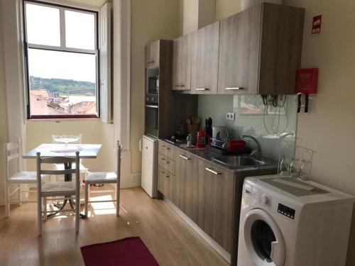 a kitchen with a washing machine next to a table at Sweet Love Family in Coimbra