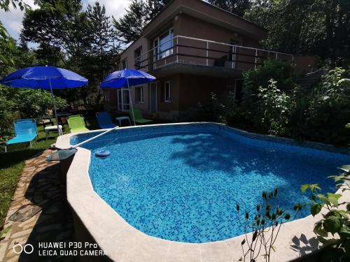 a swimming pool with an umbrella and a house at Villa Aqua in Pravets