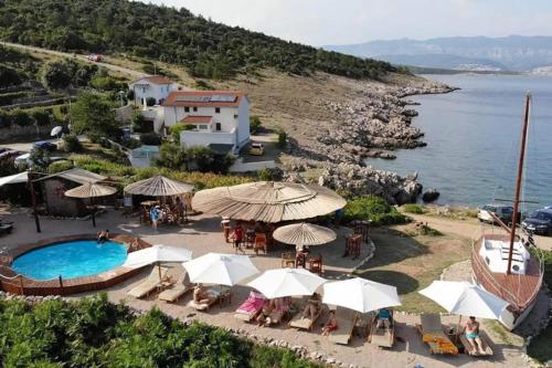 a pool with umbrellas and tables and chairs next to the water at Studio apartman Braco in Risika