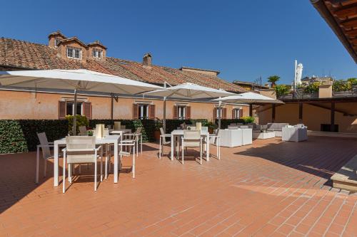 a patio with tables and white chairs and umbrellas at Harry's Bar Trevi Hotel & Restaurant in Rome