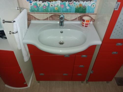 a bathroom with a white sink and red cabinets at LANELU apartman in Rogoznica