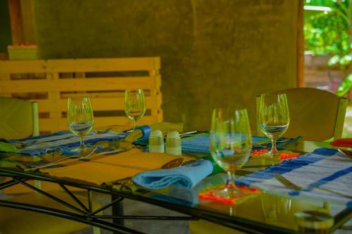 a glass table with wine glasses on top of it at Richards Cabanas in Tissamaharama