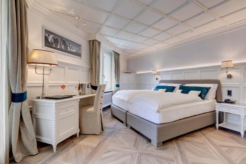 a bedroom with a large white bed and a desk at Grand Hôtel des Alpes in Chamonix-Mont-Blanc