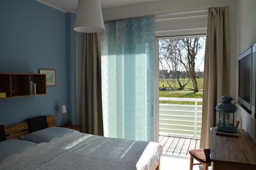 a bedroom with a bed and a sliding glass door at LeinenLos im Kajüting in Dierhagen
