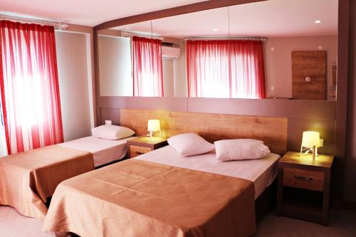 two beds in a hotel room with red curtains at Ferah Hotel in Patara