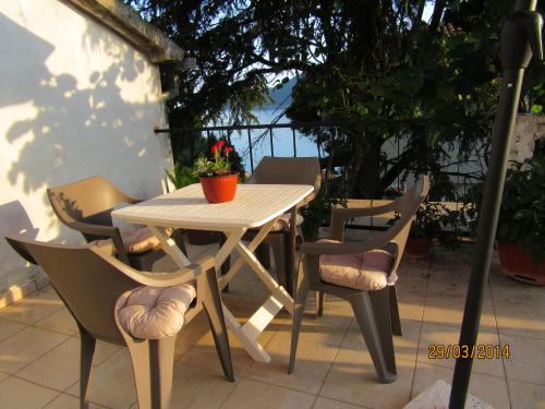 einen weißen Tisch und Stühle mit einer Pflanze auf der Terrasse in der Unterkunft Kuća Anka in Herceg-Novi