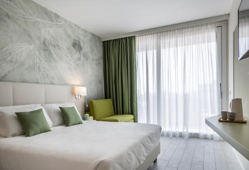 a hotel room with a bed and a green chair at Hotel Amburgo in Bibione