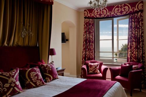 a bedroom with a large window and a bed and chairs at The Royal Hotel in Ventnor