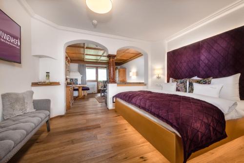 a bedroom with a large bed and a couch at Alpines Lifestyle Hotel Tannenhof in Sankt Johann im Pongau