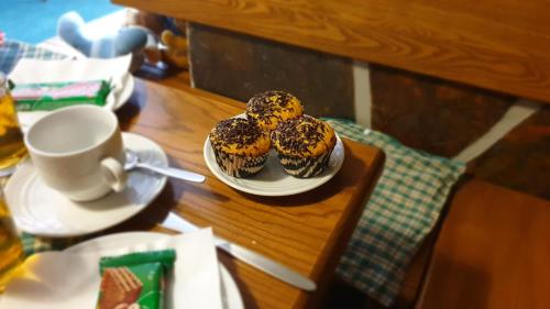 three donuts on a plate on a table with a cup of coffee at Pension Aspen Harrachov in Harrachov