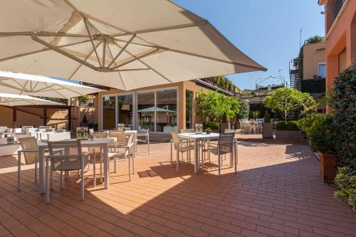 un patio esterno con tavoli, sedie e ombrelloni di Harry's Bar Trevi Hotel & Restaurant a Roma
