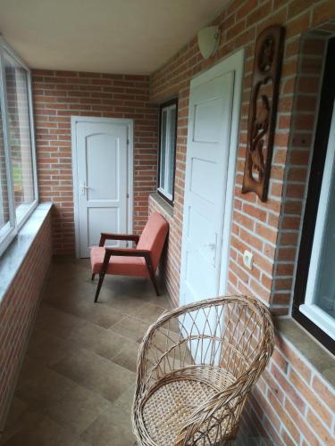 a porch with two chairs and a bench and a door at Pensiunea Colt Alb in Băile Homorod