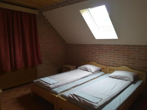two beds in a room with a window at Pensiunea Colt Alb in Băile Homorod
