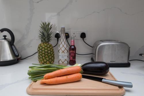a cutting board with carrots and a knife and a pineapple at Fig Tree Bay Residences 1 Lantiana Villa in Protaras