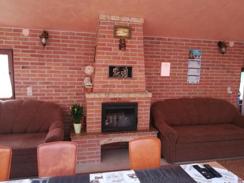 a living room with two couches and a brick fireplace at Pensiunea Colt Alb in Băile Homorod