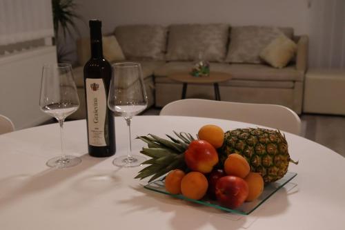 a plate of fruit on a table with wine glasses at Apartman F&F in Otočac