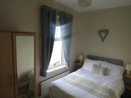 a bedroom with a white bed and a window at Meadowville Self-Catering in Cushendall