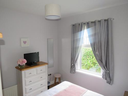 a bedroom with a bed and a window at Meadowville Self-Catering in Cushendall