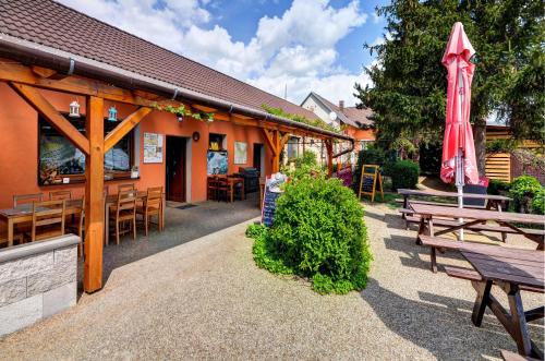 een restaurant met banken en tafels en een rode paraplu bij Privat Bohemia in Šatov