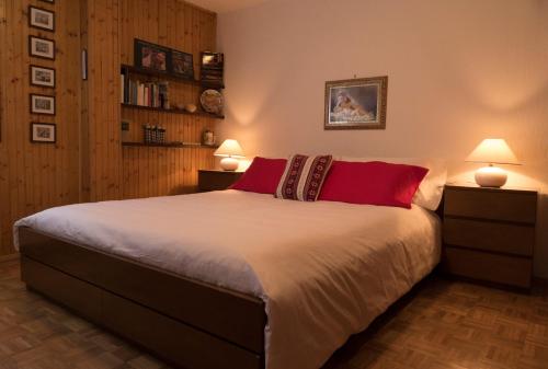1 dormitorio con 1 cama grande con almohadas rojas en AUGUSTA casa vacanza, en La Thuile