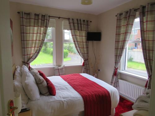 a bedroom with a bed and two windows at Meadowville Self-Catering in Cushendall